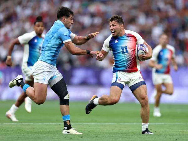 Pemain Prancis Antoine Dupont (kanan) berusaha melepaskan diri dari penjagaan pemain Uruguay pada hari pertama turnamen rugby sevens di Olimpiade Paris, Rabu (24/7). (Foto: AFP)