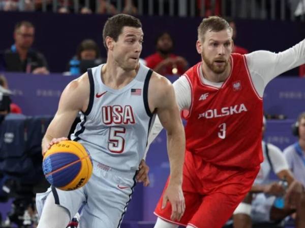 Pemain AS Jimmer Fredette (kiri) coba menerobos pertahanan Polandia dalam pertandingan penyisihan grup bola basket 3x3 putra Olimpiade Paris pada Rabu (31/7). (Foto: AP)