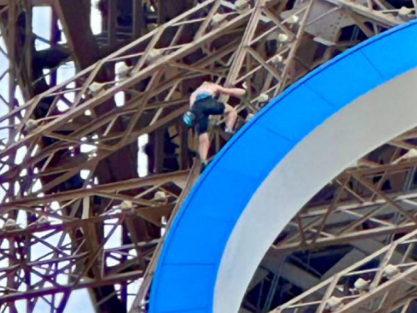 Seorang pria bertelanjang dada terlihat tepat di atas cincin Olimpiade yang menghiasi bagian kedua Menara Eiffel. (Foto: Reuters)