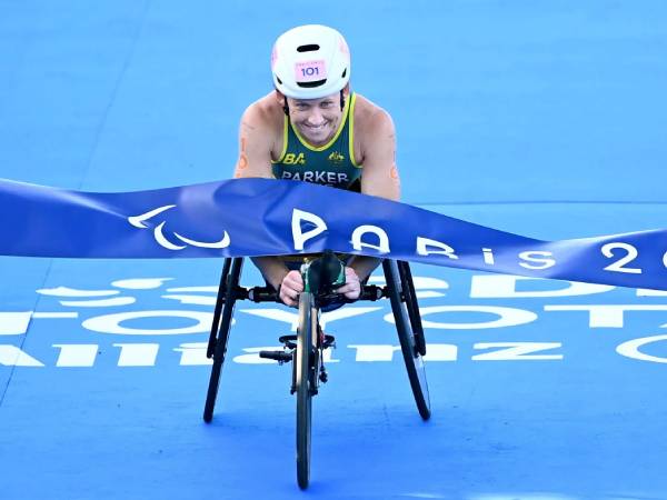 Lauren Parker tersenyum saat melewati garis finis dan memastikan sebagai juara triathlon PTWC di Paralimpiade Paris. (Foto: AP)