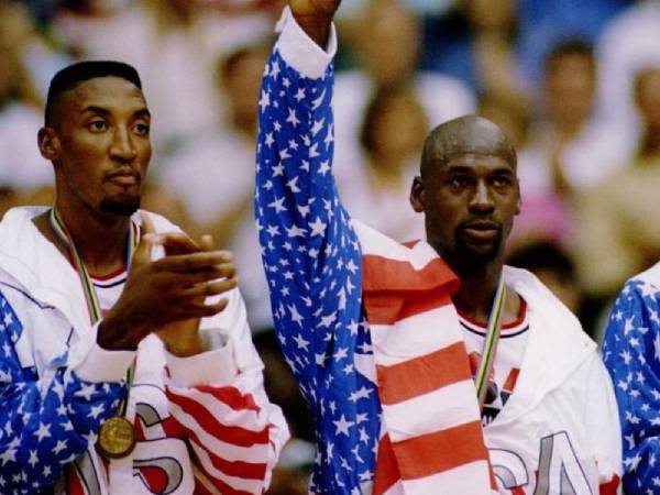 Momen ikonik saat Michael Jordan (kanan) menerima medali emas di Barcelona dengan mengalungkan bendera Amerika di bahunya. (Foto: AFP)