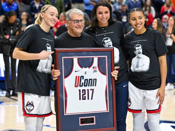 Pemain Connecticut Huskies, Paige Bueckers (kiri) dan Azzi Fudd (kanan) merayakannya bersama pelatih Geno Auriemma setelah mencetak rekor kemenangan terbanyak sepanjang masa di NCAA. (Foto: AP)