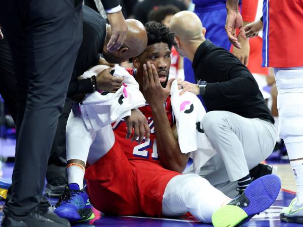 Joel Embiid terduduk di lantai sambil memegangi wajahnya setelah terkena sikutan pemain Pacers. (Foto: AP)