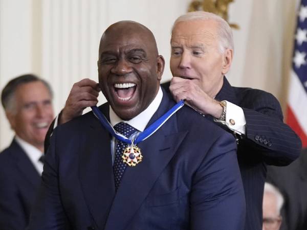 Magic Johnson (kiri) menerima medali Presidential Medal of Freedom dari Presiden AS Joe Biden. (Foto: AP)